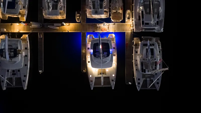 Happy Ours Yacht Photos Pics Aerial view of 2022 Lagoon 52 F yacht docked at night with blue lights.