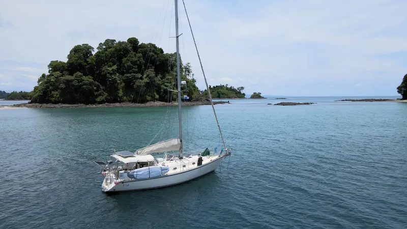 Via Yacht Photos Pics Sailboat Caliber 40 LRC SE 2004 anchored near lush island in calm blue waters.