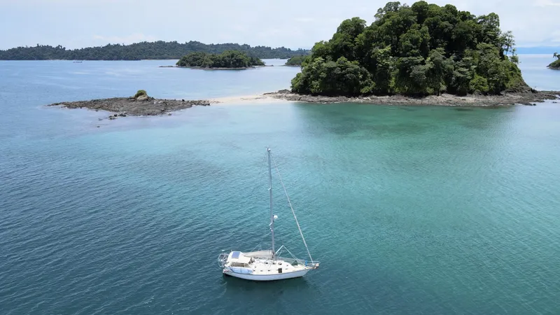 Via Yacht Photos Pics Sailboat Caliber 40 LRC SE, 2004, anchored near lush island in turquoise waters.