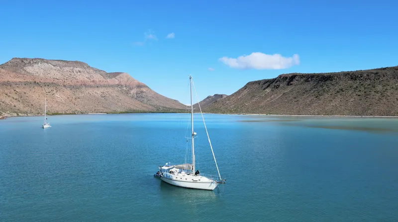Via Yacht Photos Pics Sailboat Caliber 40 LRC SE 2004 on tranquil blue water, surrounded by scenic mountains.
