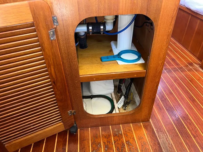 Via Yacht Photos Pics Wooden cabinet interior on 2004 Caliber 40 LRC SE boat, showing plumbing and storage.