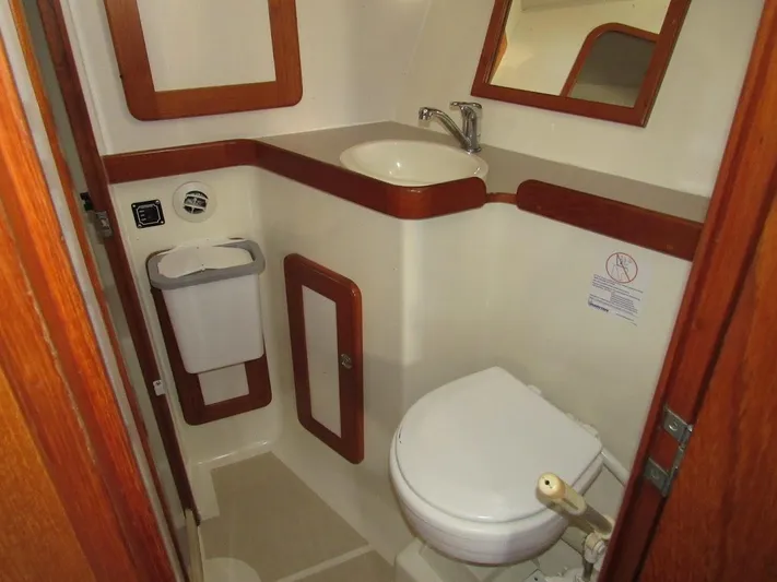 Via Yacht Photos Pics Compact bathroom in 2004 Caliber 40 LRC SE yacht with sink, toilet, and wood accents.