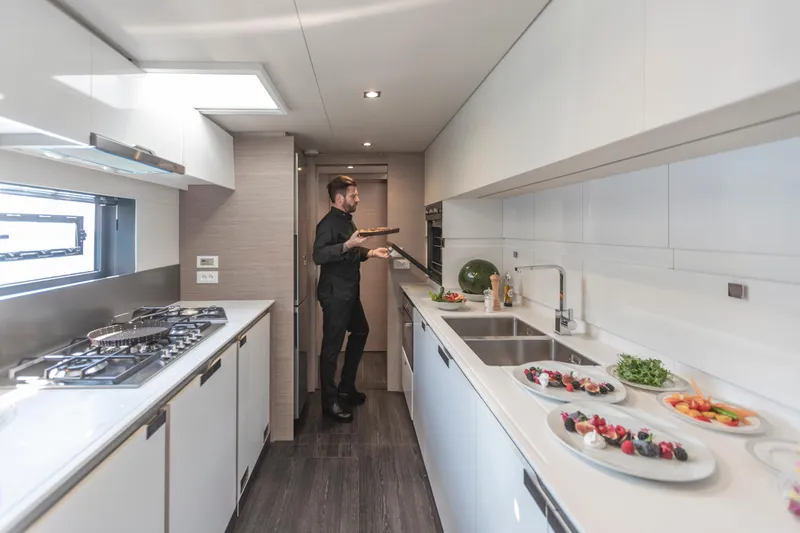 Samana 59 In St.thomas. Ex-factory Nov 2025 Yacht Photos Pics Modern kitchen in 2024 Fountaine Pajot Samana 59 yacht with chef preparing food.