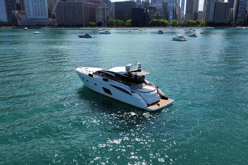  Yacht Photos Pics Luxurious 2015 Princess V62-S yacht cruising on a sunny day near a city skyline.