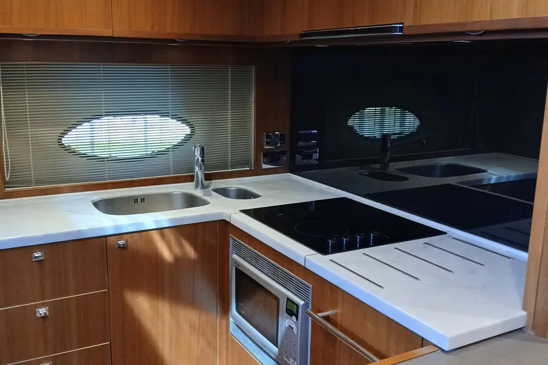  Yacht Photos Pics Modern kitchen interior of 2015 Princess V62-S yacht with sleek appliances and wooden cabinetry.