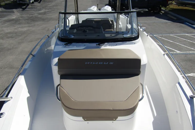  Yacht Photos Pics 2025 Nimbus Tender 9 boat with cushioned seating and windshield, parked in a lot.