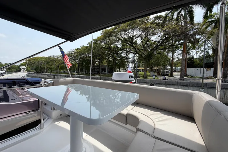  Yacht Photos Pics Luxurious 2023 Ferretti Yachts 500 deck with seating and table, docked near lush greenery.