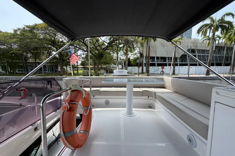  Yacht Photos Pics 2023 Ferretti Yachts 500 flybridge with seating, table, and life preserver, docked near palm trees.