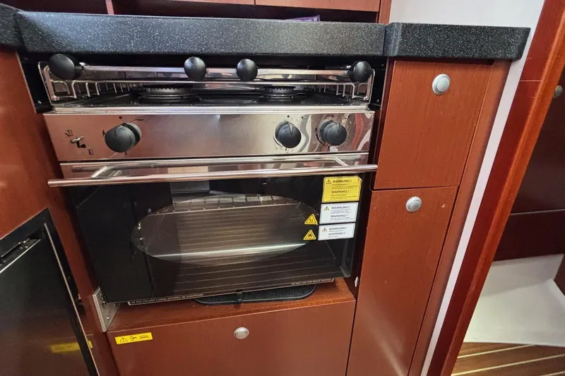 Respite Yacht Photos Pics Stove and oven in 2014 Hanse 345 yacht kitchen, featuring wooden cabinetry.