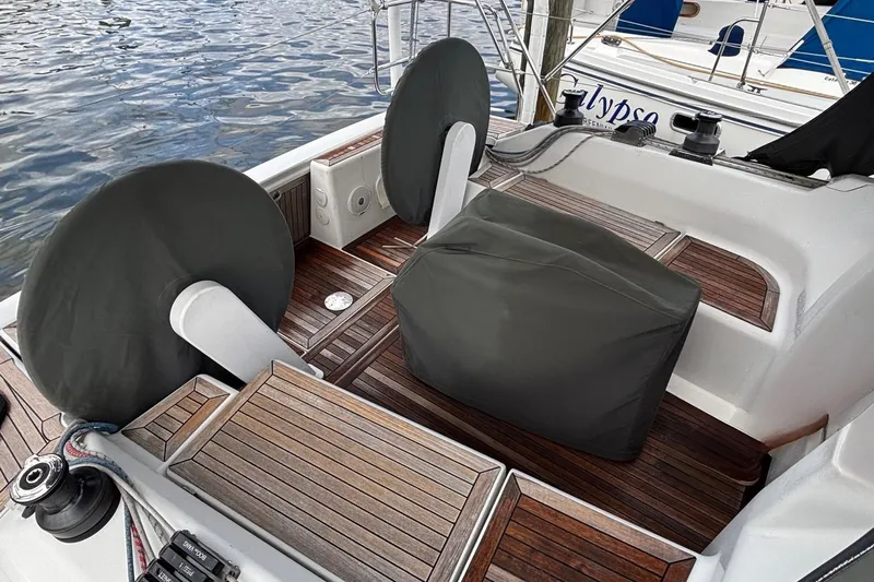 Respite Yacht Photos Pics 2014 Hanse 345 yacht cockpit with covered steering wheels and seating, docked by the water.