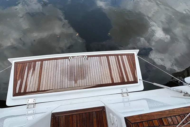 Respite Yacht Photos Pics Teak deck of 2014 Hanse 345 yacht reflecting cloudy sky on water.
