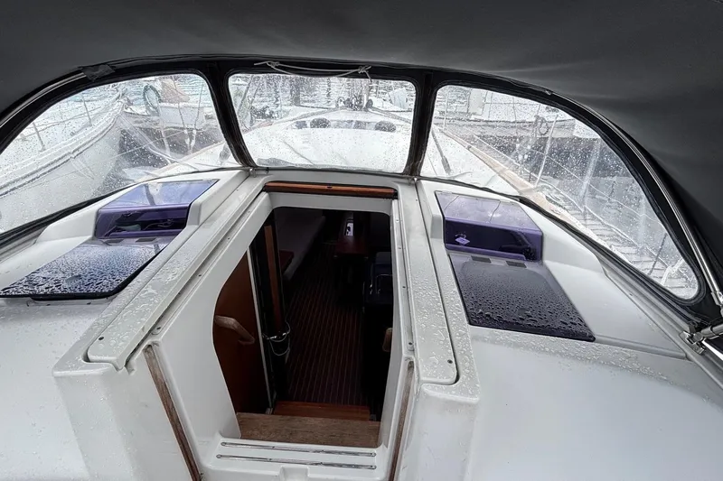 Respite Yacht Photos Pics 2014 Hanse 345 yacht cockpit with open hatch, showing interior and rain-covered surfaces.