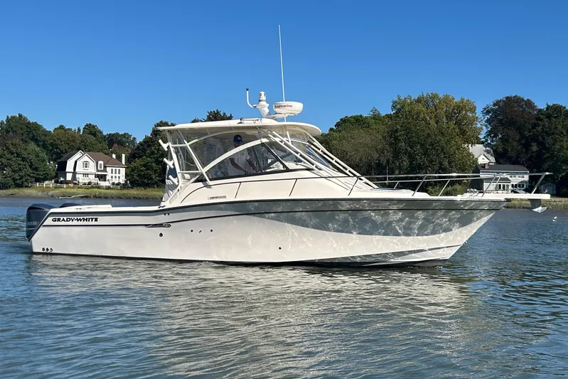  Yacht Photos Pics 2016 Grady-White Express 330 boat on calm water, with houses and trees in the background.