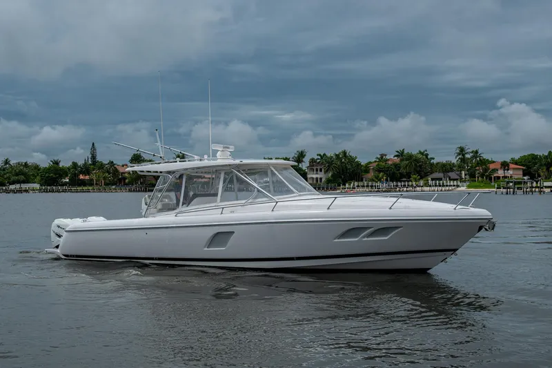  Yacht Photos Pics 2019 Intrepid 407 Cuddy boat cruising on a calm waterway under a cloudy sky.