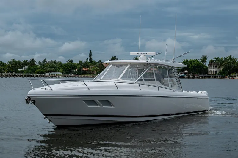  Yacht Photos Pics 2019 Intrepid 407 Cuddy boat cruising on a calm waterway under cloudy skies.