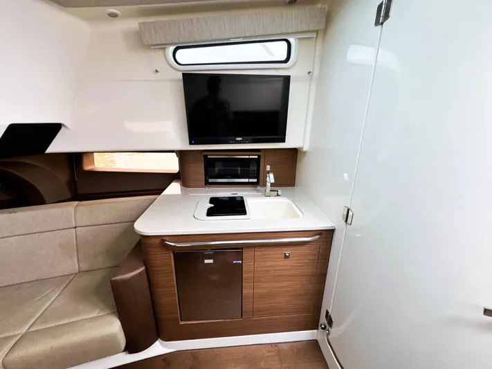 Seas The Day Yacht Photos Pics 2017 Boston Whaler 420 Outrage interior with kitchenette, TV, and seating area.