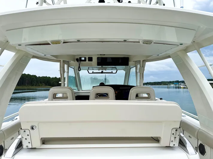 Seas The Day Yacht Photos Pics 2017 Boston Whaler 420 Outrage boat interior with seating and helm, on calm water.