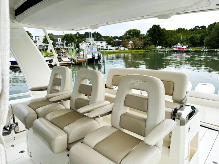 Seas The Day Yacht Photos Pics 2017 Boston Whaler 420 Outrage boat interior with luxurious seating, docked by a scenic waterfront.
