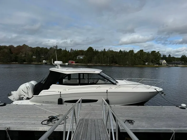 Harley Quinn Yacht Photos Pics 2023 Regal 36 XO boat docked on a serene lake with cloudy skies.
