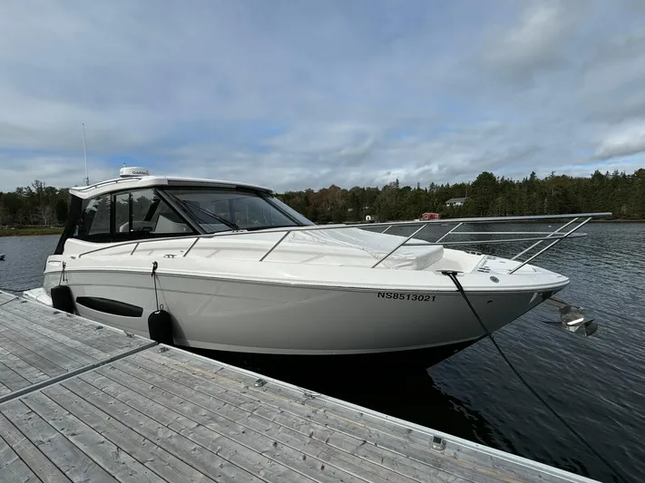 Harley Quinn Yacht Photos Pics 2023 Regal 36 XO boat docked on a calm lake under a cloudy sky.