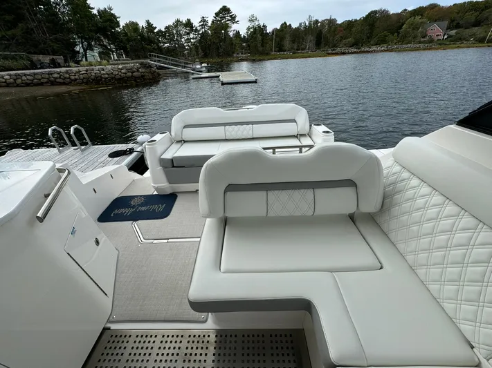 Harley Quinn Yacht Photos Pics 2023 Regal 36 XO boat interior with white seating, docked by a scenic waterfront.