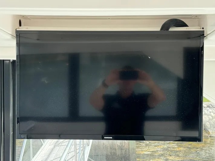 Harley Quinn Yacht Photos Pics Samsung TV on a 2023 Regal 36 XO boat, reflecting a person taking a photo.