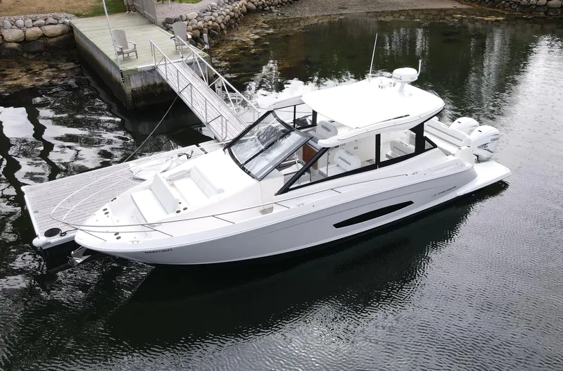 Harley Quinn Yacht Photos Pics 2023 Regal 36 XO boat docked on calm water near a wooden pier.