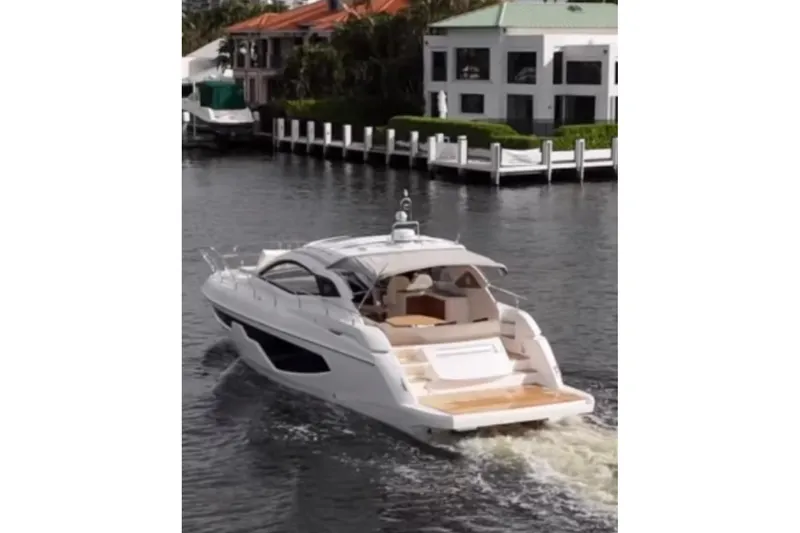  Yacht Photos Pics 2024 Sessa Marine C44 Cruiser navigating a canal near waterfront homes.