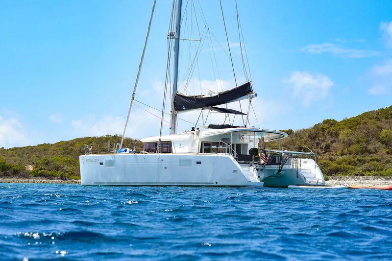 Rapscallion Yacht Photos Pics 2018 Lagoon 450 F catamaran sailing near a scenic coastline under a clear blue sky.
