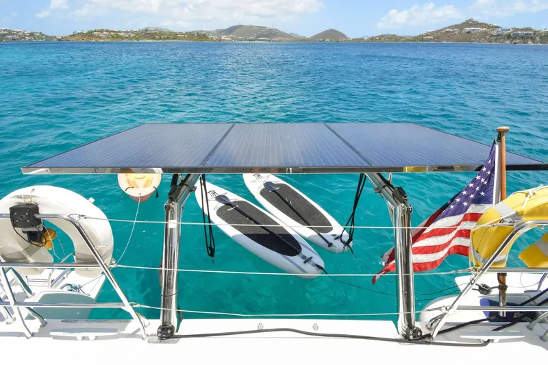 Rapscallion Yacht Photos Pics 2018 Lagoon 450 F catamaran with solar panels, paddleboards, and American flag on turquoise water.