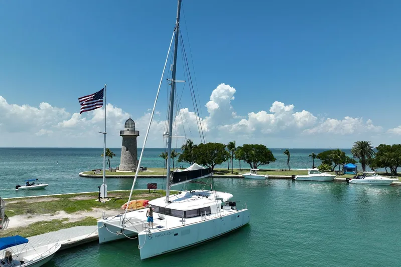 Rapscallion Yacht Photos Pics 2018 Lagoon 450 F catamaran docked near lighthouse, American flag waving, sunny day.