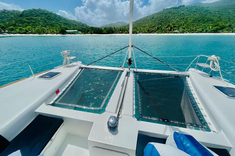 Rapscallion Yacht Photos Pics Lagoon 450 F catamaran, 2018 model, anchored in turquoise waters near lush green hills.