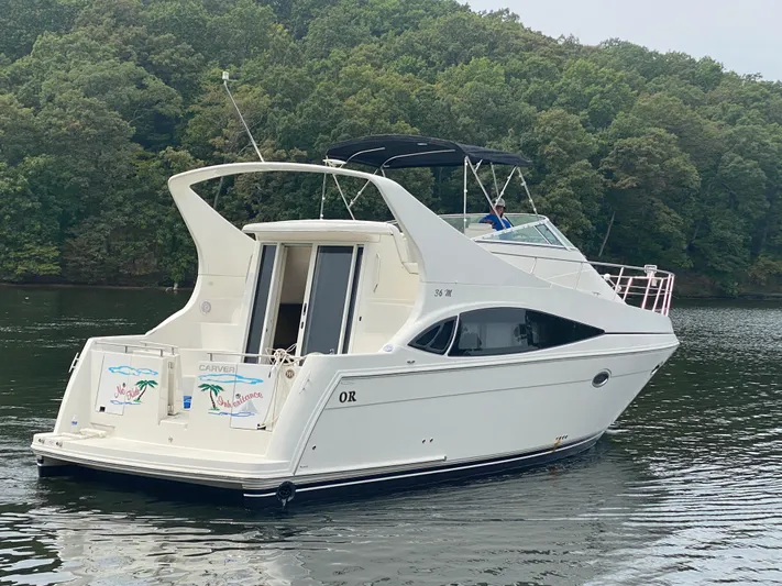  Yacht Photos Pics 2006 Carver 36 Mariner yacht on a serene lake with lush green trees.