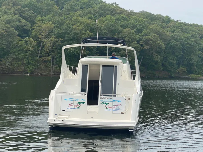  Yacht Photos Pics 2006 Carver 36 Mariner yacht on a serene lake with lush forest backdrop.