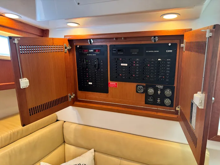 Fishy Business Yacht Photos Pics Electrical control panel inside a 2005 Cabo 35 Express boat, featuring wooden cabinetry.