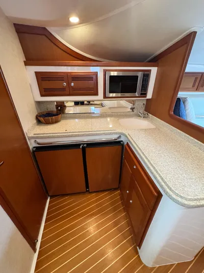 Fishy Business Yacht Photos Pics 2005 Cabo 35 Express yacht kitchen with wood cabinets, microwave, and compact fridge.