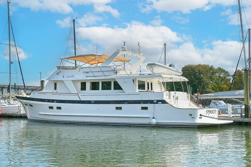 Symmetry Yacht Photos Pics 2002 Grand Alaskan Flushdeck yacht docked in a marina under a blue sky.