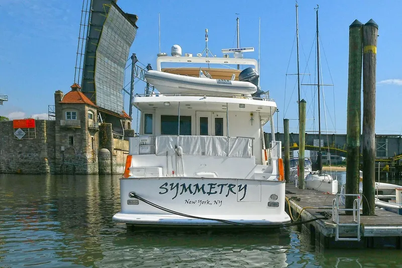 Symmetry Yacht Photos Pics Grand Alaskan Flushdeck 2002 yacht docked near a raised drawbridge, named "Symmetry."