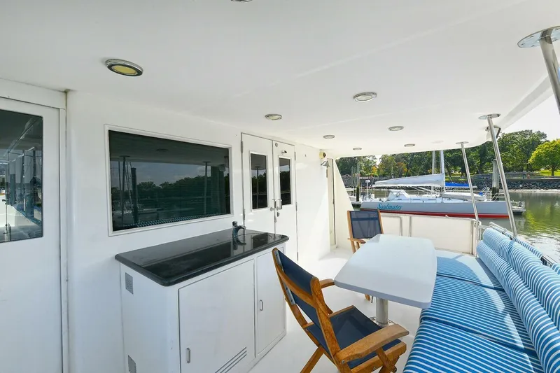 Symmetry Yacht Photos Pics 2002 Grand Alaskan Flushdeck yacht deck with seating and table, docked near sailboats.