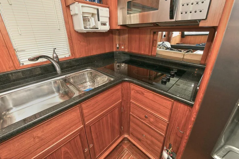 Symmetry Yacht Photos Pics 2002 Grand Alaskan Flushdeck yacht kitchen with wood cabinetry, stainless steel sink, and electric stove.