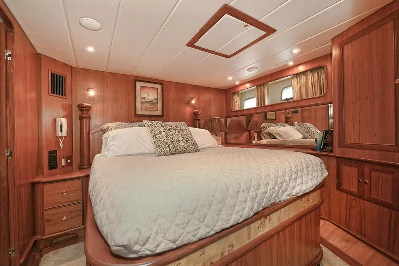 Symmetry Yacht Photos Pics Luxurious 2002 Grand Alaskan Flushdeck yacht bedroom with elegant wood paneling and cozy bedding.