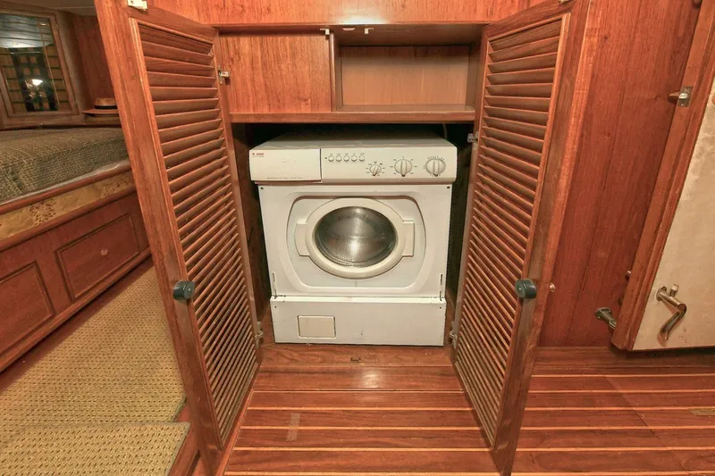 Symmetry Yacht Photos Pics Laundry area with washer in 2002 Grand Alaskan Flushdeck yacht, featuring wooden cabinetry.