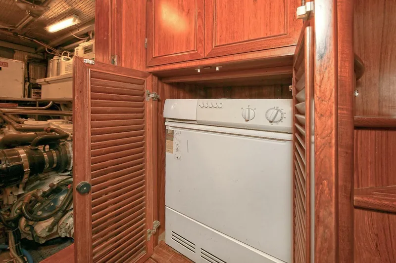 Symmetry Yacht Photos Pics Laundry area inside 2002 Grand Alaskan Flushdeck yacht with wooden cabinetry.