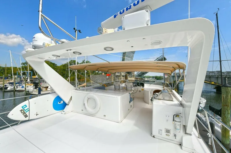 Symmetry Yacht Photos Pics 2002 Grand Alaskan Flushdeck yacht with spacious deck, docked at marina under clear blue sky.