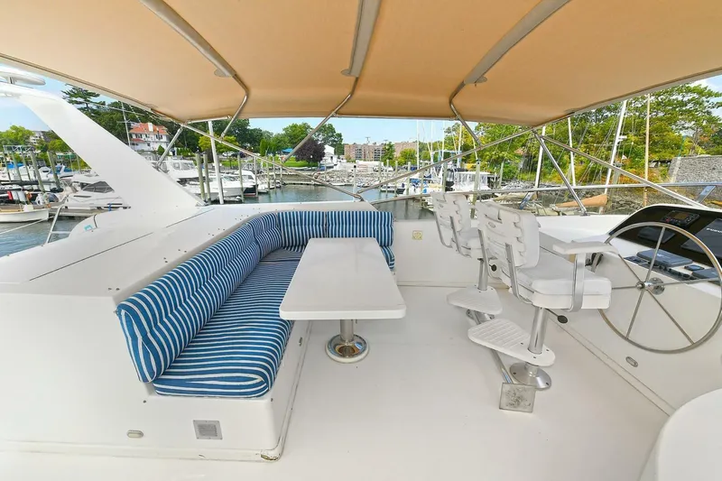 Symmetry Yacht Photos Pics 2002 Grand Alaskan Flushdeck yacht with striped seating and helm, docked at marina.