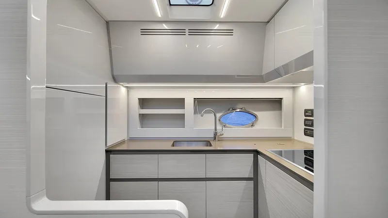  Yacht Photos Pics Modern kitchen interior of 2020 Pershing 62 yacht with sleek cabinetry and porthole window.