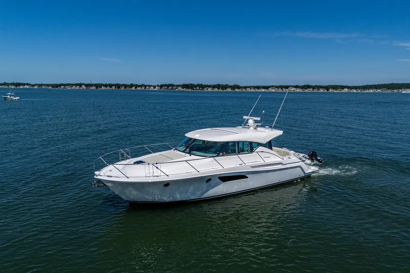  Yacht Photos Pics 2020 Tiara Yachts C44 Coupe cruising on open water under clear blue skies.