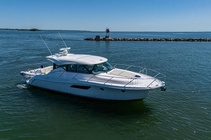  Yacht Photos Pics 2020 Tiara Yachts C44 Coupe cruising on calm waters under clear blue skies.