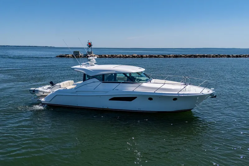  Yacht Photos Pics 2020 Tiara Yachts C44 Coupe cruising on open water under clear blue skies.