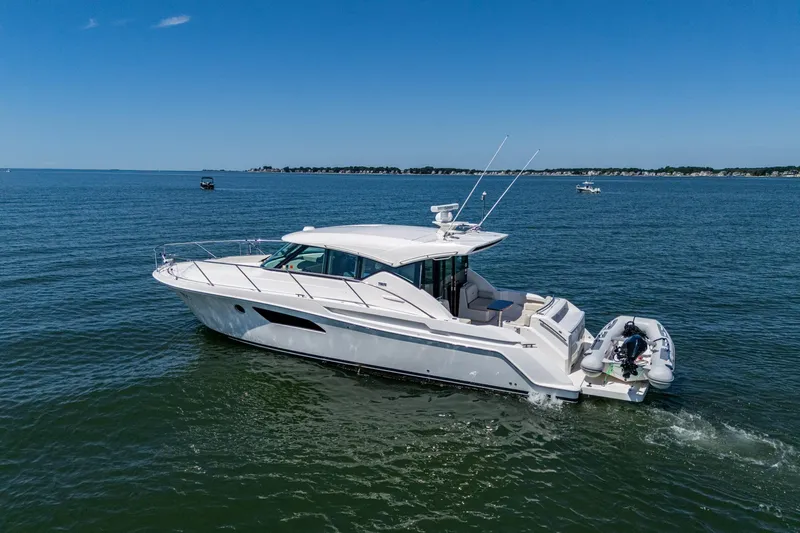  Yacht Photos Pics 2020 Tiara Yachts C44 Coupe cruising on open water under clear blue skies.
